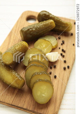 Marinated pickled cucumber on cutting board on white background. Vertical photo Marinated pickled cucumber on cutting board on white background. Vertical photo 128872972