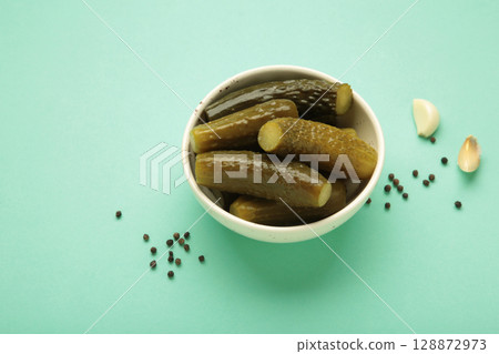 Marinated pickled cucumber with garlic on mint background. 128872973