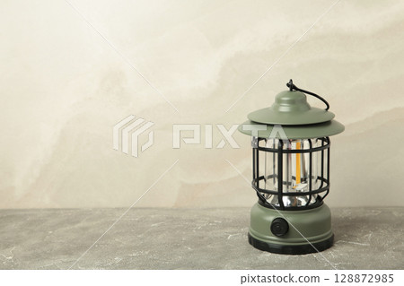 Hand holding lantern lamp on light background. Camping Hand holding lantern lamp on light background. Camping 128872985
