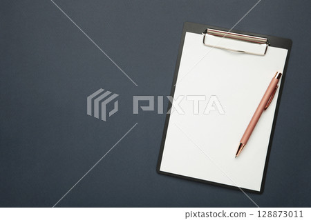 Black tablet with piece of empty paper and pen on dark blue background. Space for text Black tablet with piece of empty paper and pen on dark blue background. Space for text 128873011