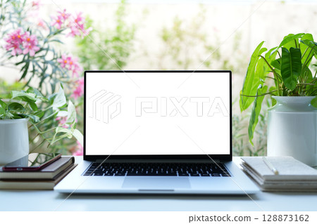 laptop and notebooks with potted plant, cozy workspace with flowers background 128873162