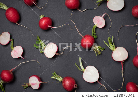 Scattered Fresh Radishes And Slices Artistically Arranged On Dark Surface Scattered Fresh Radishes And Slices Artistically Arranged On Dark Surface 128873341