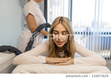 Woman in special white suit getting anti cellulite massage in a spa salon. LPG, and body contouring treatment in clinic.Reset body weight with LPG massage.  128873629