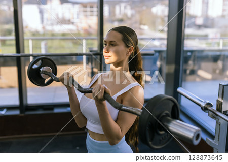 A young athletic girl does exercises using sports equipment. 128873645
