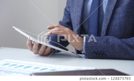 Businessman is using a digital tablet to analyze financial data, working with modern technology in the office for strategic corporate decision making and workflow optimization. Business people concept Businessman is using a digital tablet to analyze financial data, working with modern technology in the office for strategic corporate decision making and workflow optimization. Business people concept 128873765