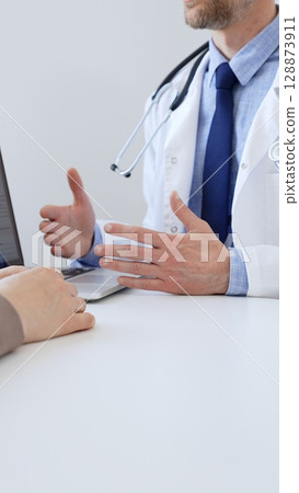 Doctor man gesturing with hands while explaining diagnosis to patient during medical consultation in clinic, healthcare and medical concept. Medicine and health care 128873911