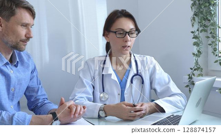 Female doctor explaining a diagnosis to a male patient, offering medical advice and support during a consultation in her office, fostering communication and trust. Medicine and health care 128874157