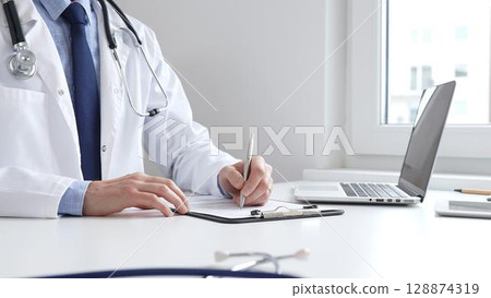 Male doctor writing a prescription and filling out medical records on a clipboard in an office setting, showcasing the essential aspects of healthcare and patient care. Medicine and health care 128874319