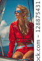 Stylish woman in red sailing outfit enjoying sunny adventure on a yacht 128875431