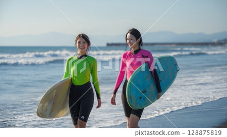 A Japanese woman walking on the beach with a surfboard 128875819