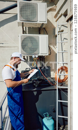 Technician inspecting rooftop air conditioning system with tools and equipment 128875989