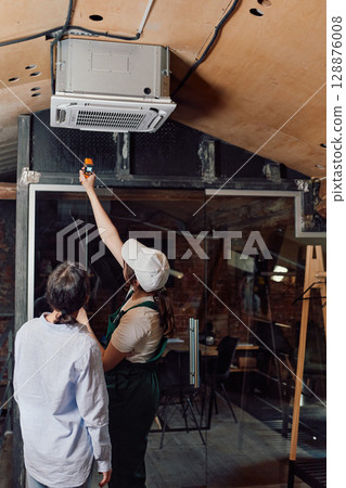 Women checking air conditioning units after installing indoors 128876008