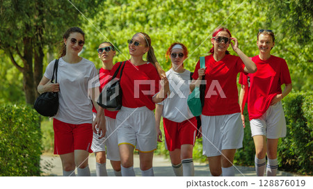 Confident female football players strolling in park wearing team uniforms 128876019