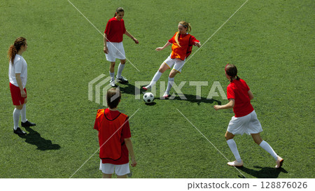 Female athletes engaging in soccer game on grassy athletic field 128876026