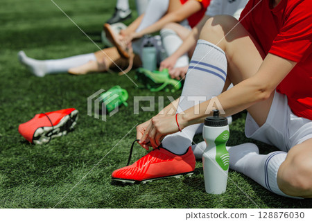 Female soccer athletes getting ready for game on sunlit field 128876030