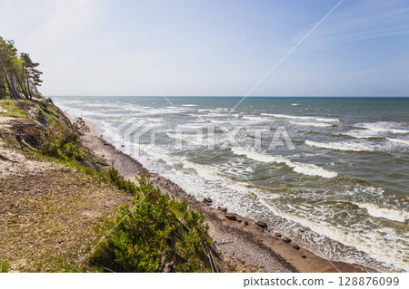 Dramatic Baltic Sea cliff coast with foamy waves and blue sky Dramatic Baltic Sea cliff coast with foamy waves and blue sky 128876099
