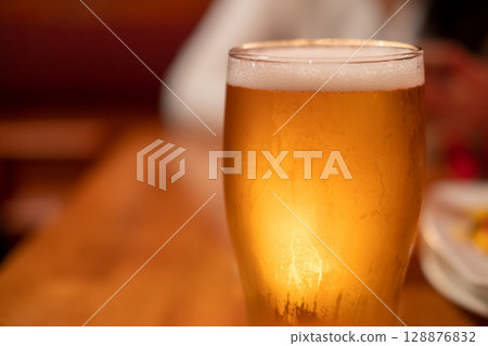 Close up of beer in a glass with blur background Close up of beer in a glass with blur background 128876832
