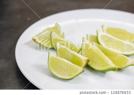 Lime slice, served on white plate for drink and cocktail 128876833