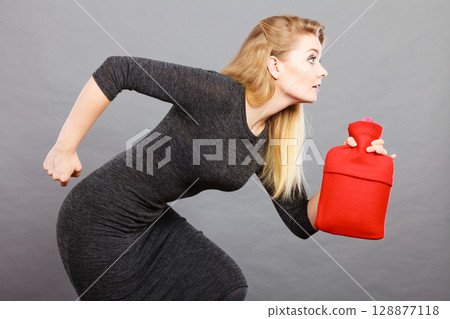 Woman runs with hot water bottle, remedy for aches 128877118