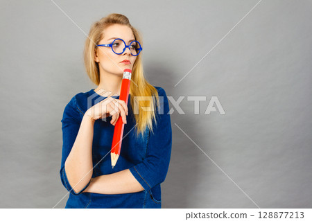 Woman confused thinking, big pencil in hand 128877213