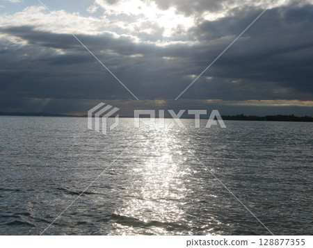 The sky is cloudy and the sun is shining on the water 128877355