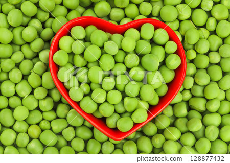 Fresh green peas in red ceramic bowl as a background. Top view. Flat lay Fresh green peas in red ceramic bowl as a background. Top view. Flat lay 128877432