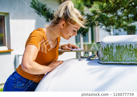 Woman checking level of propane gas in tank 128877739