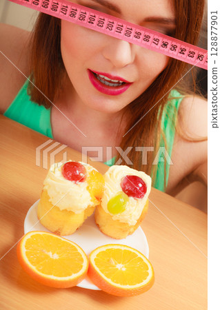 Woman with tape measure and cake. Diet dilemma. 128877901