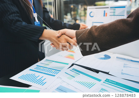 Business people shaking hands in office. Two business partners shaking hands after signing a contract in office. 128878483