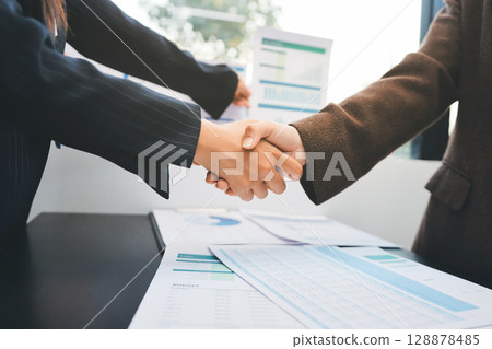 Business people shaking hands in office. Two business partners shaking hands after signing a contract in office. 128878485