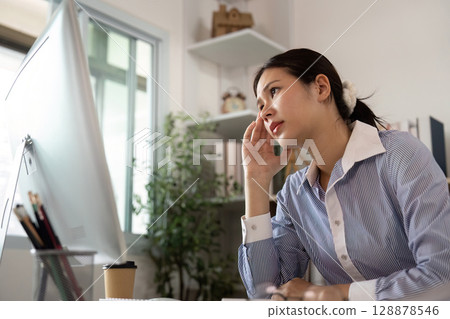 Office Syndrome: Young woman contemplating while working at her desk Office Syndrome: Young woman contemplating while working at her desk 128878546