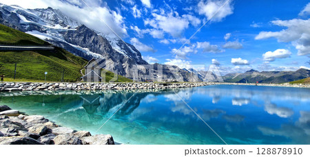 Switzerland nature . panoramic view of Fallboden lake with turquoise water and reflections of snowy peaks. Kleine Scheidegg mountain pass famous for hiking in Bernese Alps. Swiss travel 128878910