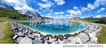 Switzerland nature . panoramic view of Fallboden lake with turquoise water and reflections of snowy peaks. Kleine Scheidegg mountain pass famous for hiking in Bernese Alps. Swiss travel 128878911