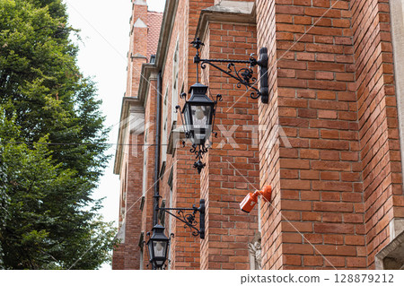 Ornate Street Lamps and Red Brick Wall on a Historic Building Ornate Street Lamps and Red Brick Wall on a Historic Building 128879212