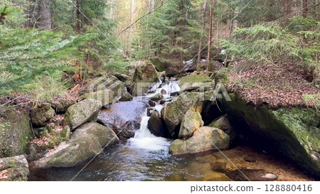 Serene and peaceful streams flowing gracefully through the rocky forest terrain landscape 128880416