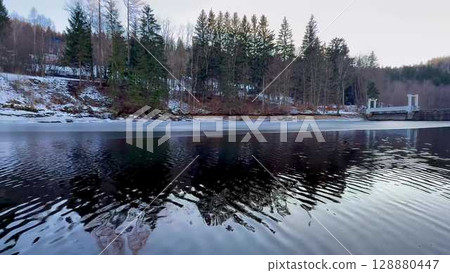 A serene winter landscape with reflective water that captures tranquility and beauty in nature 128880447
