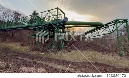 The Industrial Infrastructure Featuring a Green Pipeline Stands Out Against a Dramatic Sky The Industrial Infrastructure Featuring a Green Pipeline Stands Out Against a Dramatic Sky 128880470