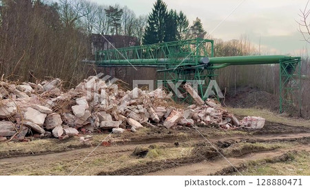 A collapsed industrial structure surrounded by debris and heavy machinery scattered everywhere A collapsed industrial structure surrounded by debris and heavy machinery scattered everywhere 128880471