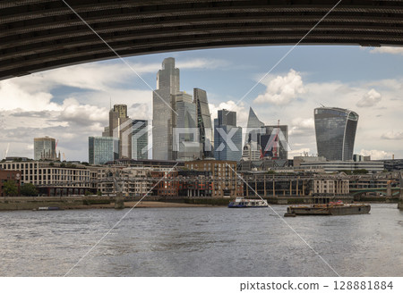 a panoramic view of the London skyline, featuring prominent modern skyscrapers and buildings situated along the River Thames. 128881884