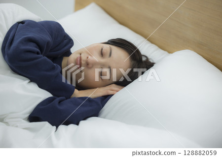 A woman sleeping in bed A woman sleeping in bed 128882059