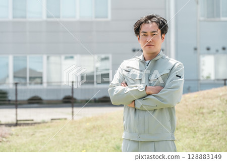 A middle-aged male worker in work clothes standing in front of his company A middle-aged male worker in work clothes standing in front of his company 128883149