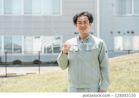 A middle-aged male worker in work clothes standing in front of his company A middle-aged male worker in work clothes standing in front of his company 128883150