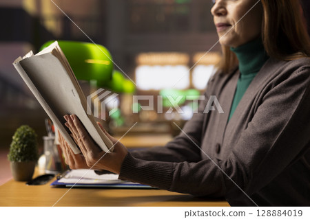College student preparing for an academic lecture with specialty books, studying a book and gathering knowledge in a scholarly environment designed for learning. Campus library. 128884019