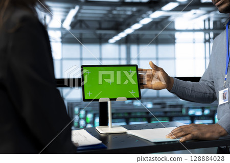 Admins in data center use mockup tablet, inspecting server rackmounts, updating network topologies, close up shot. IT specialists talking, using chroma key device, ensuring stable operations 128884028