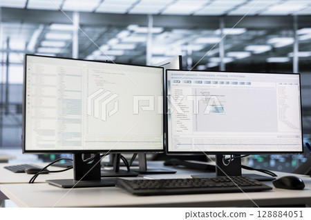 Close up of computer displays in empty high tech data center monitoring hardware energy consumption. PC monitors on desk used for checking potential system failures in server room 128884051