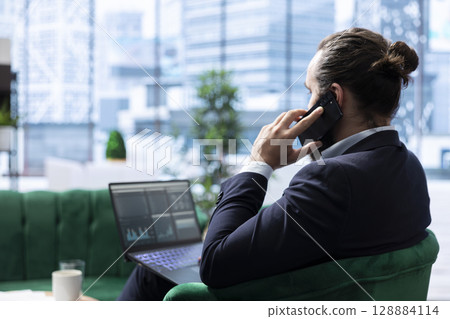 CEO discusses a potential partnership over the phone with investors, briefing them about the company sales numbers. Boss aligning strategic business ideas to ensure enterprise growth. 128884114
