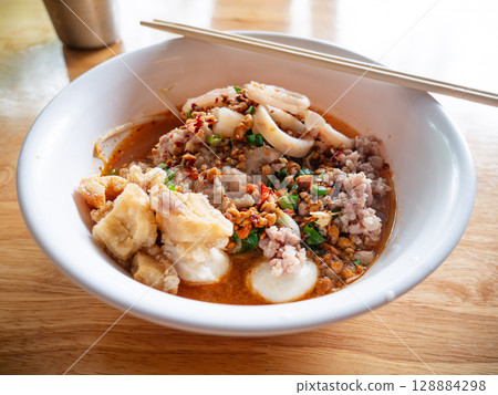 Tom Yum Seafood Noodles with Crispy Pork Cracklings or Pork Rinds. 128884298