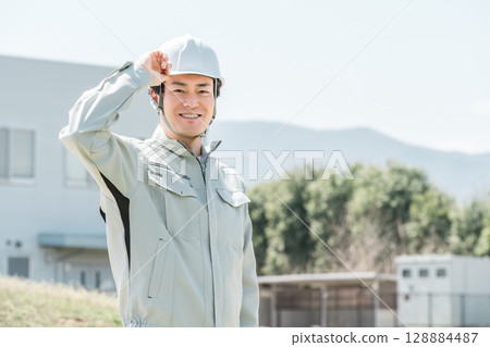 Asian male worker wearing work clothes and a helmet Asian male worker wearing work clothes and a helmet 128884487