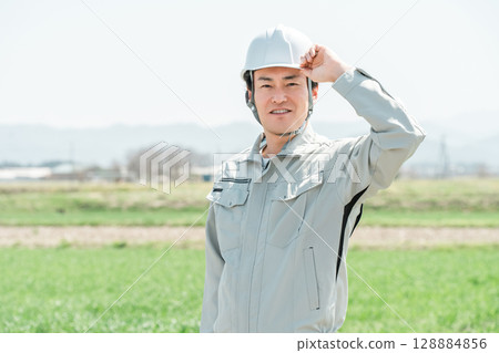 Middle-aged workers, craftsmen and site supervisors in work clothes standing in a rural rice field 128884856