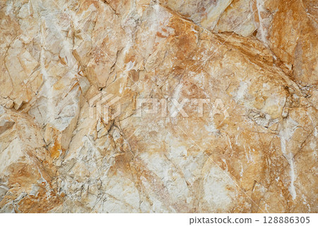 Natural surface of a marble quarry wall with rough textured stone. Natural surface of a marble quarry wall with rough textured stone. 128886305